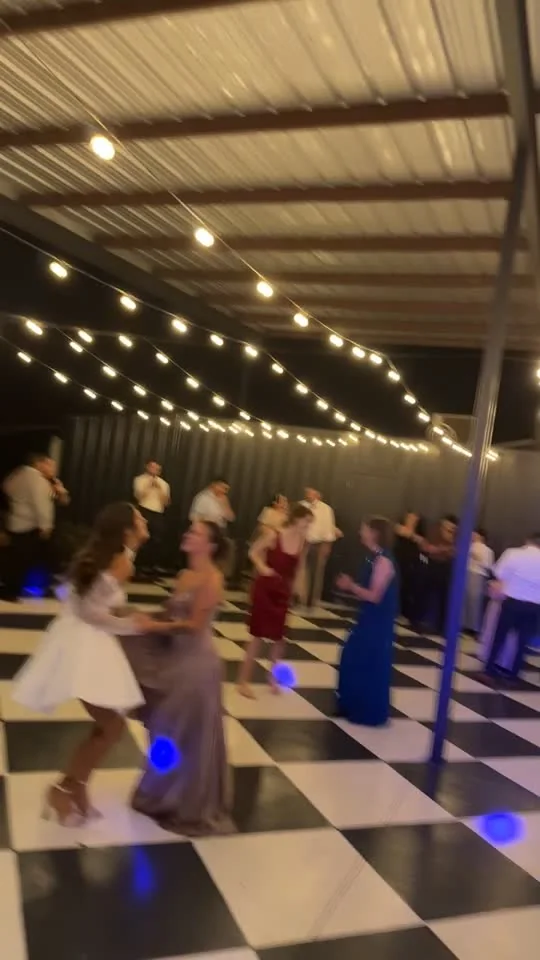 Guests dancing under string lights and blue dance-floor lighting at a Central Texas event