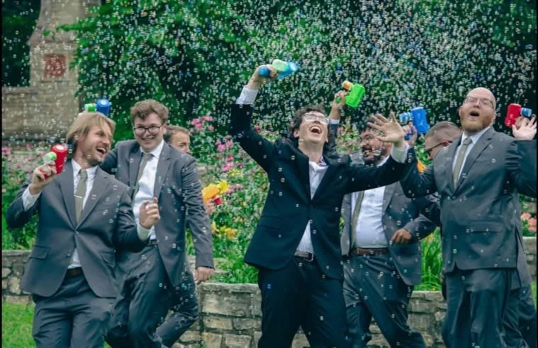 Groomsmen laughing with bubble guns at a Texas wedding